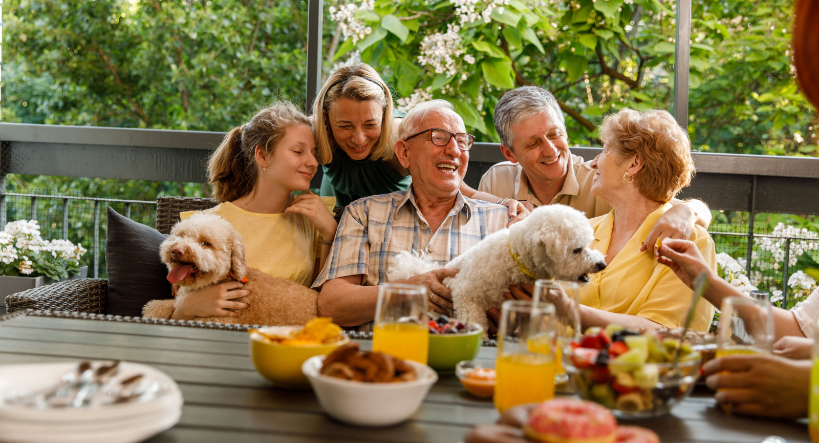 Three generations happy family enjoying a meal with a spoiled dog.